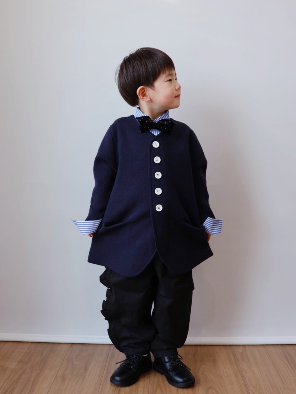 ブルー系のノーカラージャケット、ブルー系のシャツ/ブラウス、ブラック系のチノパンツを着用したキッズの冬コーディネートの2枚目の写真