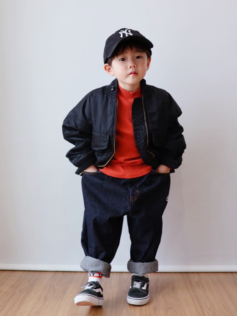 オレンジ系のトップス、ブラック系のジャケット/アウター、ブルー系のデニムパンツを着用したキッズの冬コーディネートの5枚目の写真