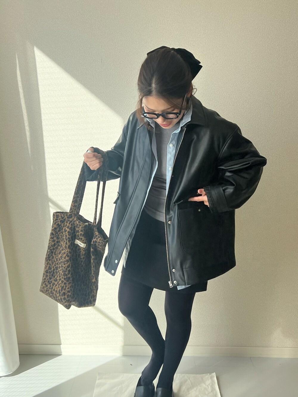 ブラウン系のトートバッグ、ブラック系のジャケット/アウターを着用したレディースの冬コーディネートの2枚目の写真