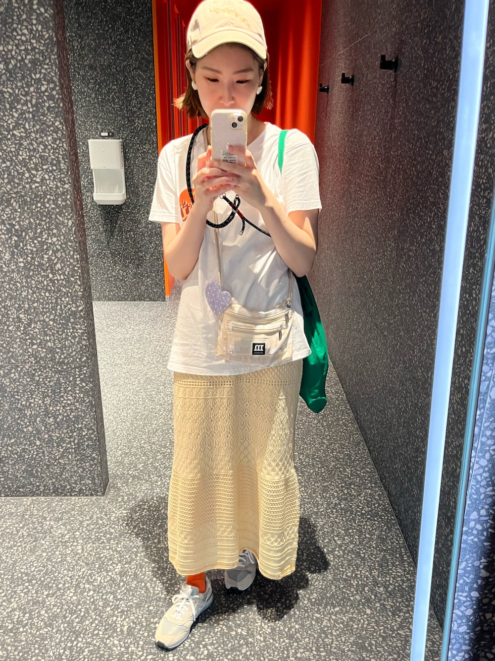 グレー系のスニーカー、ベージュ系のショルダーバッグ、イエロー系のスカートを着用したレディースの春コーディネートの2枚目の写真