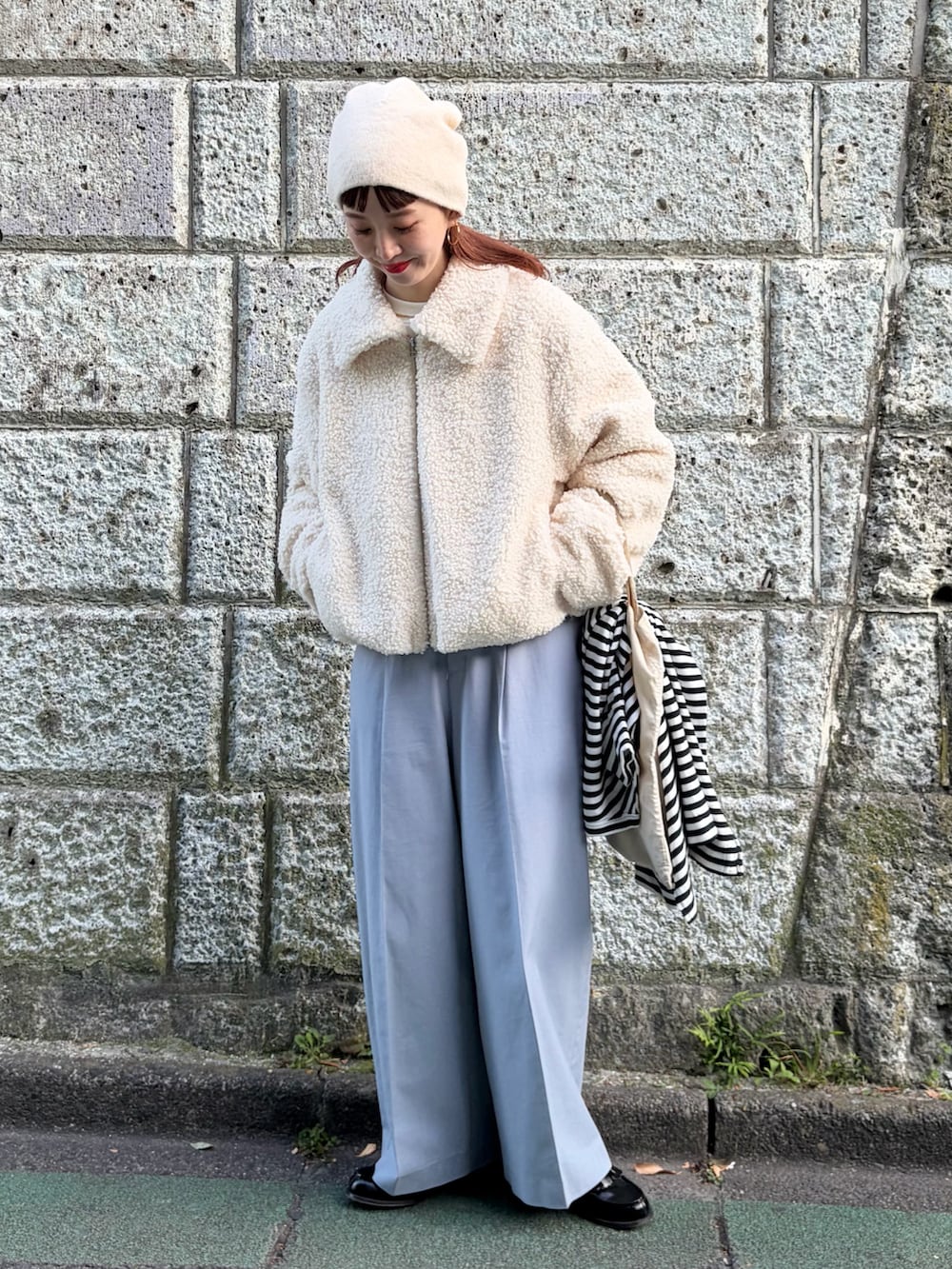 ホワイト系のブルゾン、ブルー系のスラックス、ホワイト系のニットキャップ/ビーニーを着用したレディースの秋コーディネートの2枚目の写真