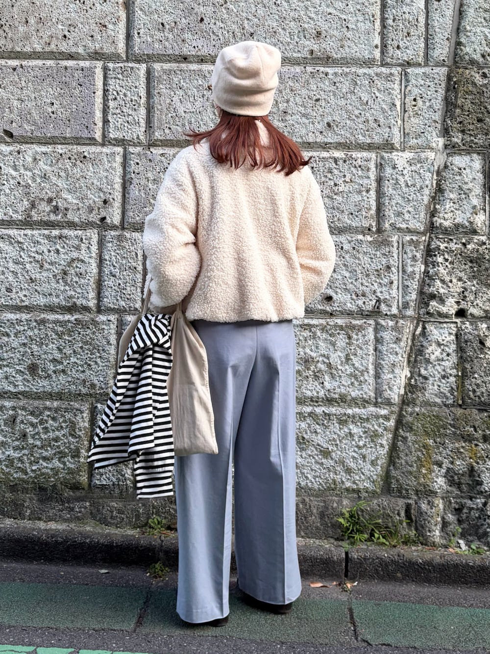 ホワイト系のブルゾン、ブルー系のスラックス、ホワイト系のニットキャップ/ビーニーを着用したレディースの秋コーディネートの4枚目の写真