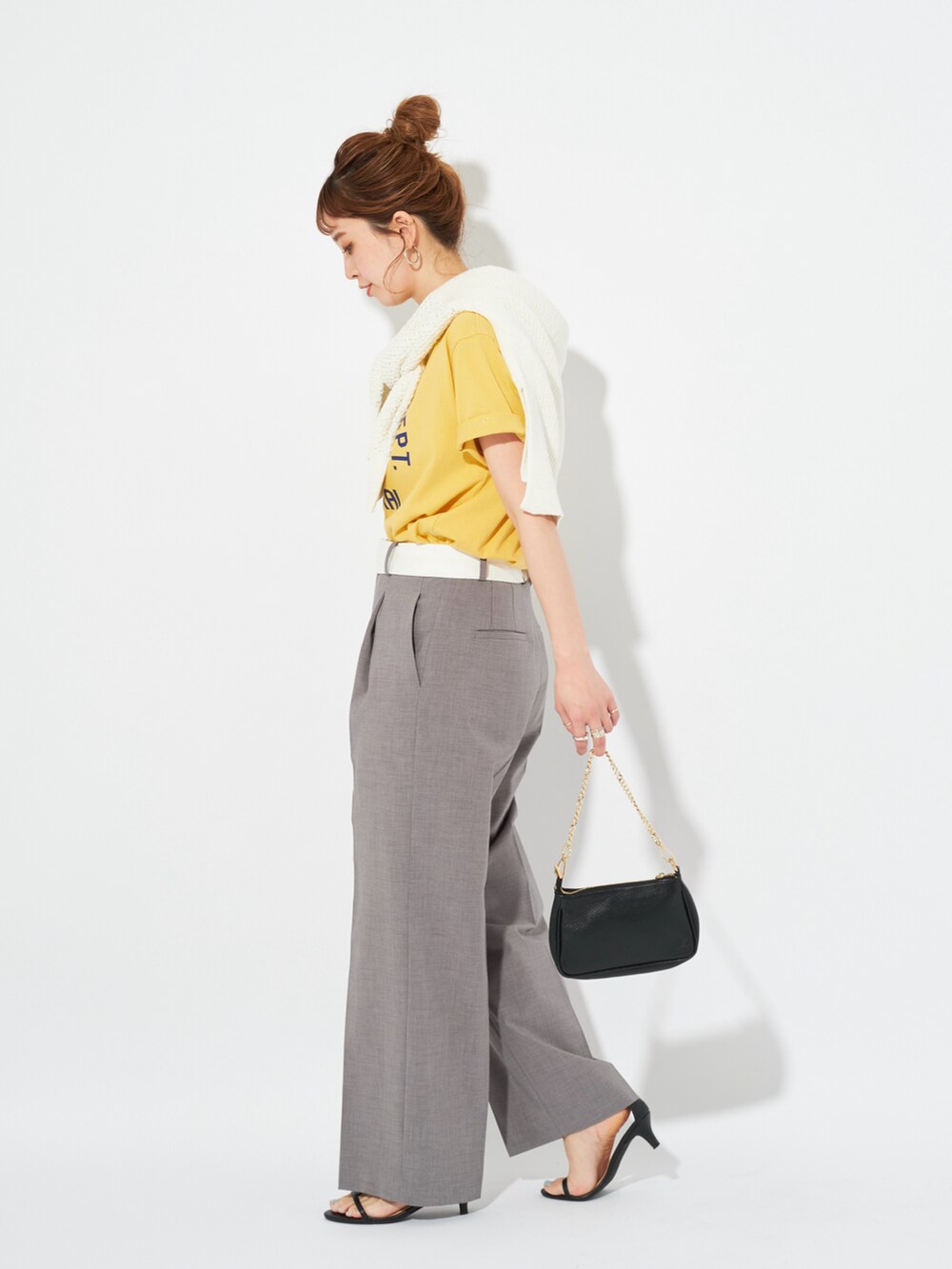 イエロー系のTシャツ/カットソー、ホワイト系のニット/セーター、グレー系のスラックスを着用したレディースの春コーディネートの2枚目の写真