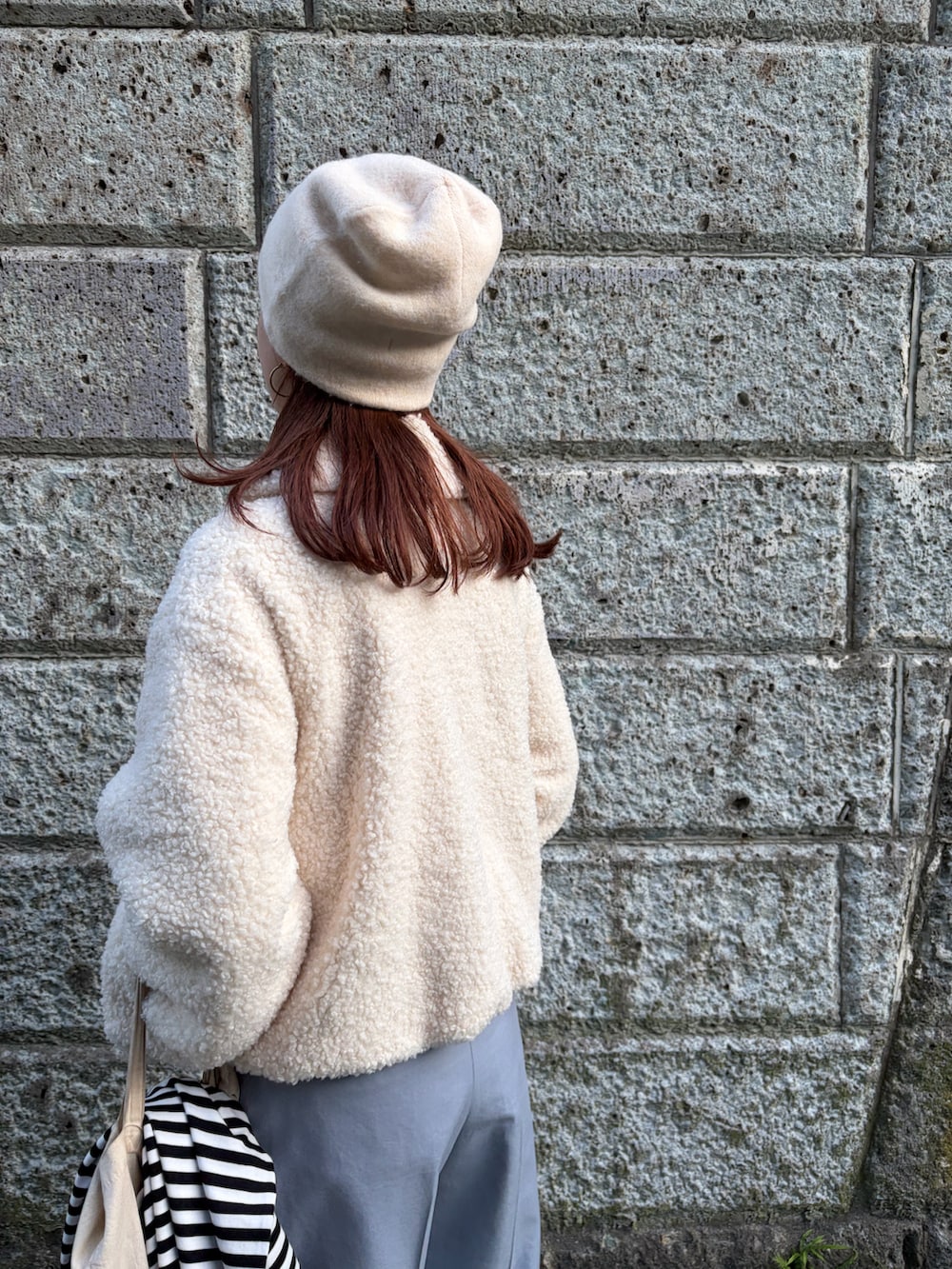 ホワイト系のブルゾン、ブルー系のスラックス、ホワイト系のニットキャップ/ビーニーを着用したレディースの秋コーディネートの5枚目の写真