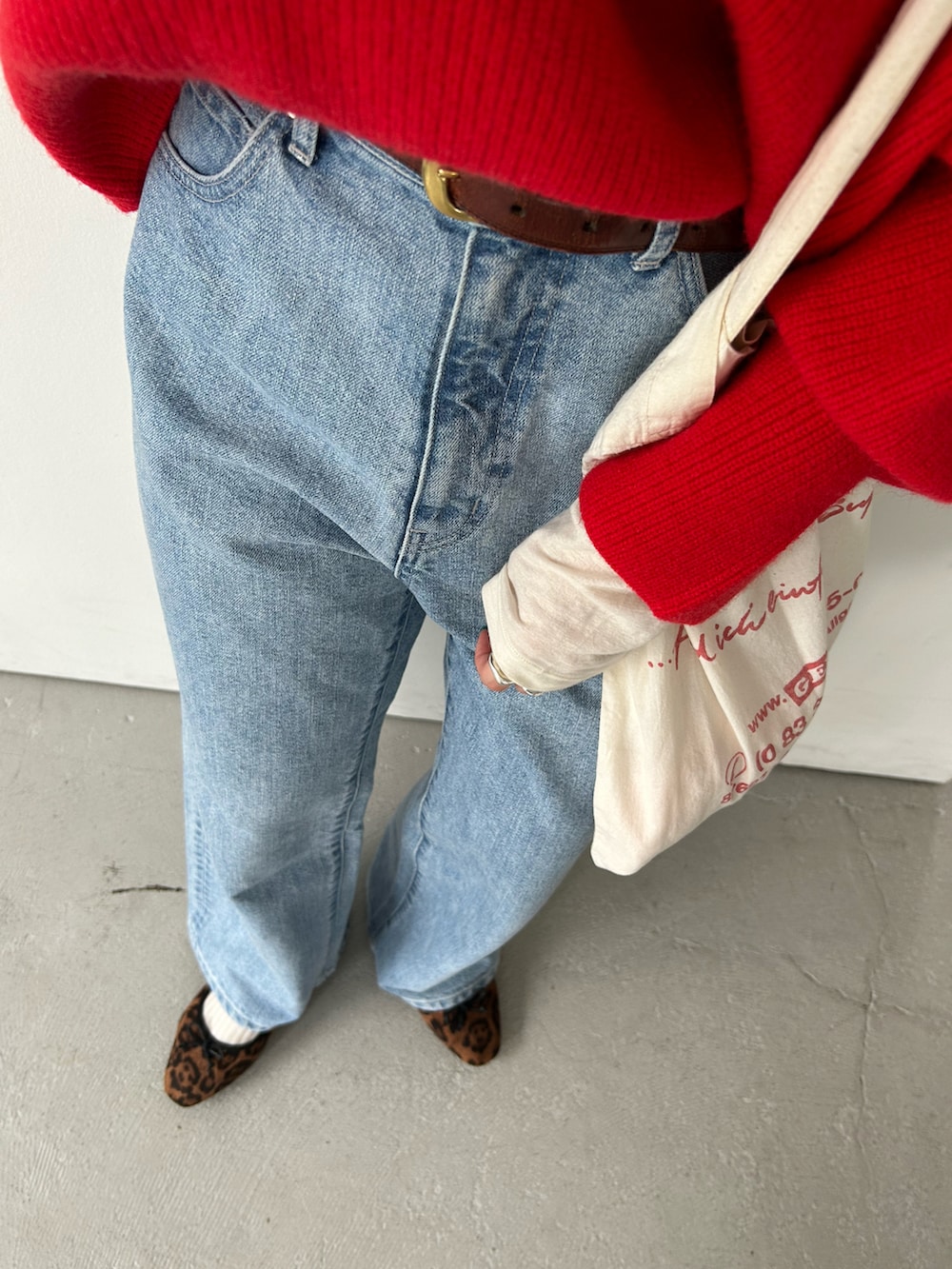 レッド系のニット/セーター、ホワイト系のTシャツ/カットソー、ブルー系のデニムパンツを着用したレディースの秋コーディネートの3枚目の写真