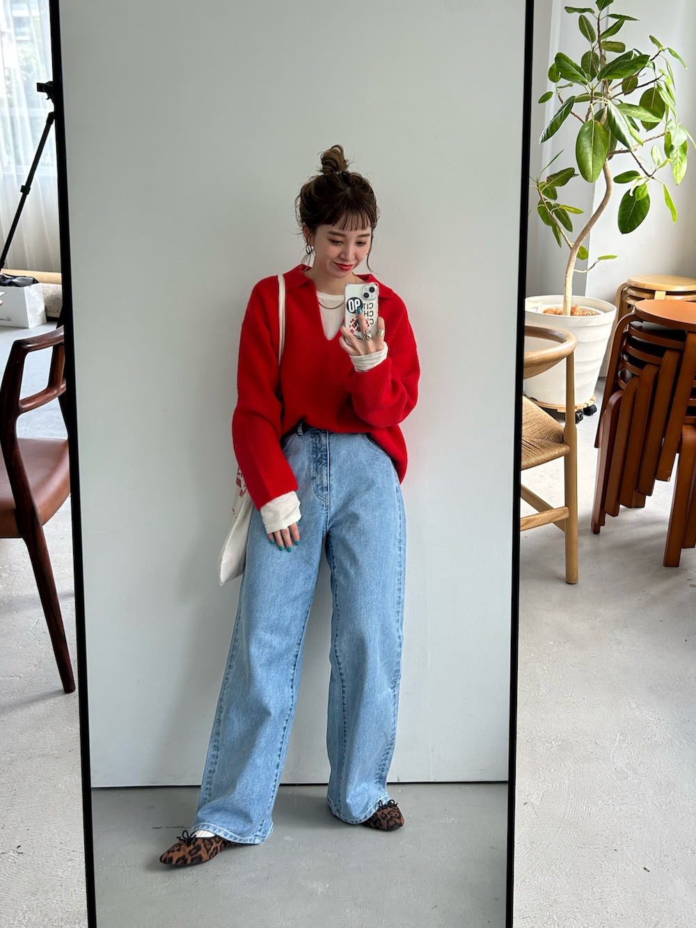 レッド系のニット/セーター、ホワイト系のTシャツ/カットソー、ブルー系のデニムパンツを着用したレディースの秋コーディネートの2枚目の写真