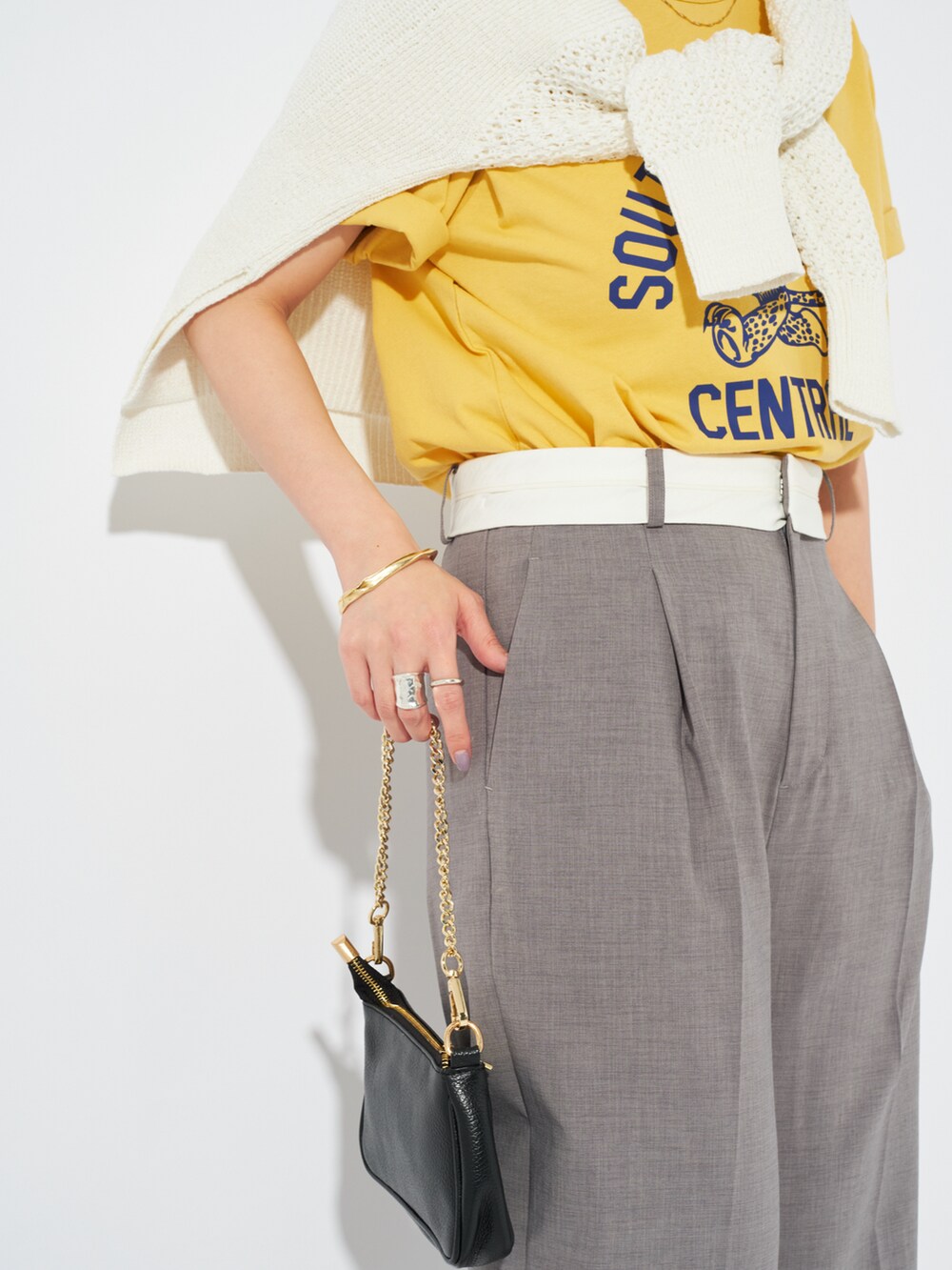 イエロー系のTシャツ/カットソー、ホワイト系のニット/セーター、グレー系のスラックスを着用したレディースの春コーディネートの5枚目の写真