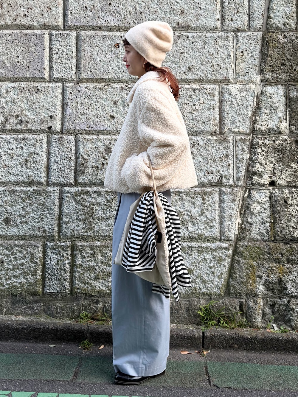 ホワイト系のブルゾン、ブルー系のスラックス、ホワイト系のニットキャップ/ビーニーを着用したレディースの秋コーディネートの3枚目の写真