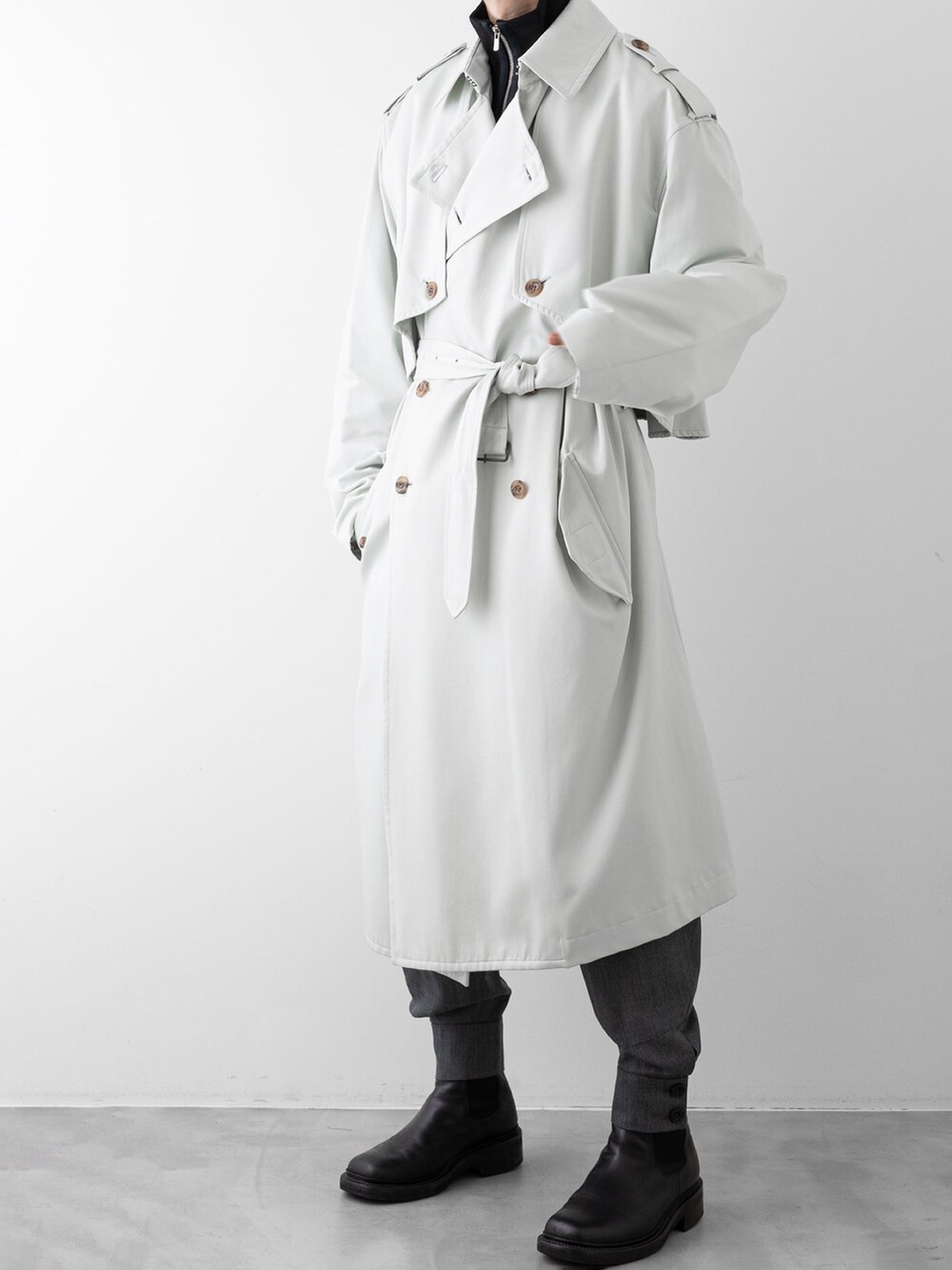 グレー系のその他パンツ、ブラック系のニット/セーター、グリーン系のトレンチコートを着用したメンズの秋コーディネートの5枚目の写真