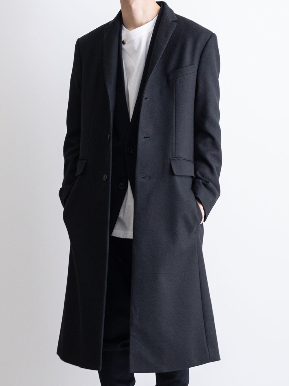 ブラック系のチェスターコート、ブルー系のその他パンツ、ブルー系のノーカラージャケットを着用したメンズの冬コーディネートの3枚目の写真