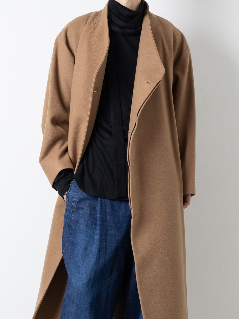 ブルー系のデニムパンツ、ベージュ系のステンカラーコート、ブラック系のTシャツ/カットソーを着用したメンズの秋コーディネートの2枚目の写真