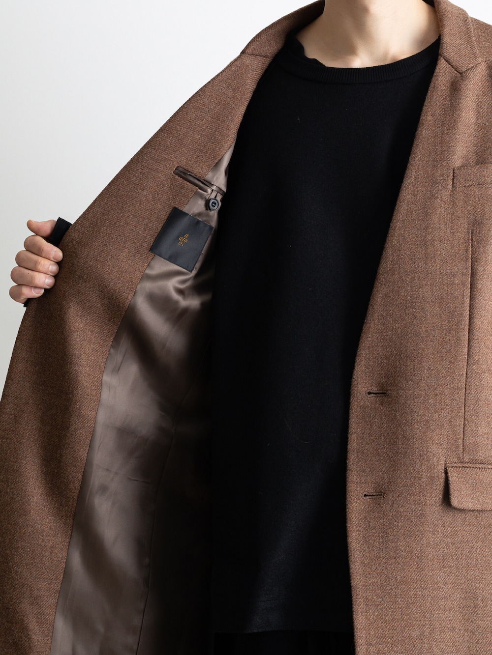 ブラウン系のノーカラージャケット、ブラック系のその他パンツ、ブラック系のTシャツ/カットソーを着用したメンズの冬コーディネートの3枚目の写真