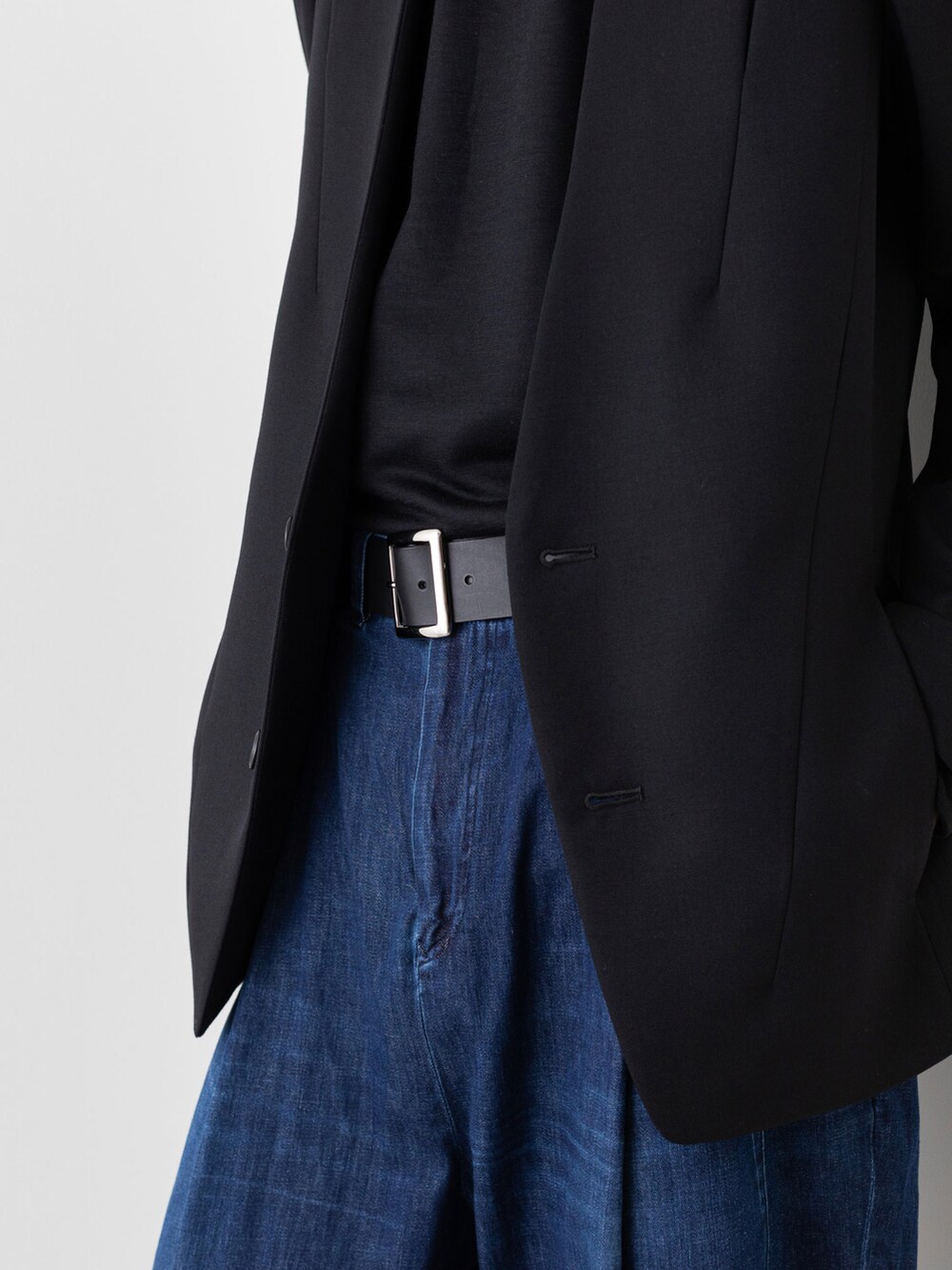 ブルー系のデニムパンツ、ブラック系のノーカラージャケット、ブラック系のニット/セーターを着用したメンズの秋コーディネートの4枚目の写真