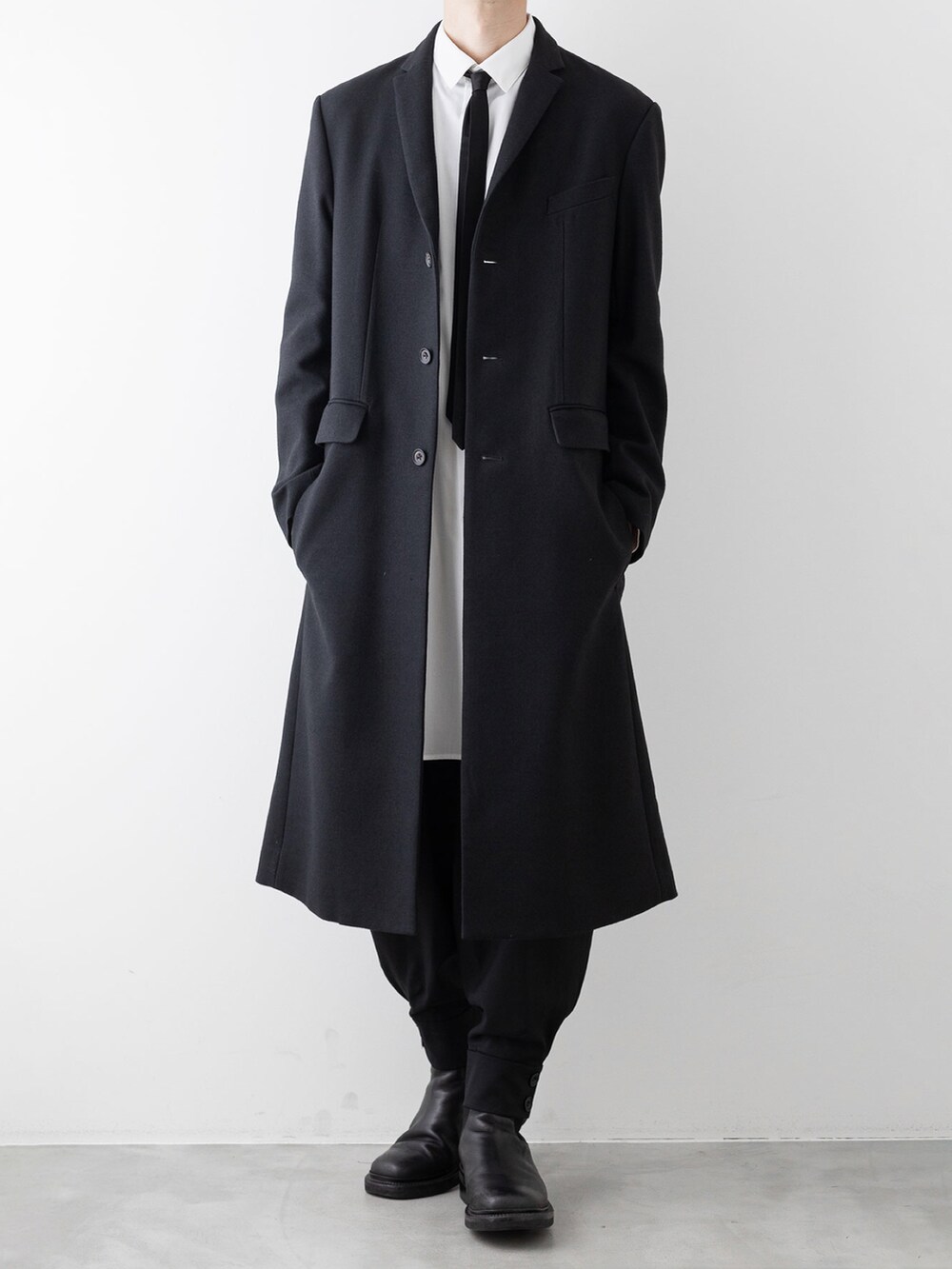 ブラック系のチェスターコート、ホワイト系のシャツ/ブラウス、ブラック系のその他パンツを着用したメンズの秋コーディネートの5枚目の写真