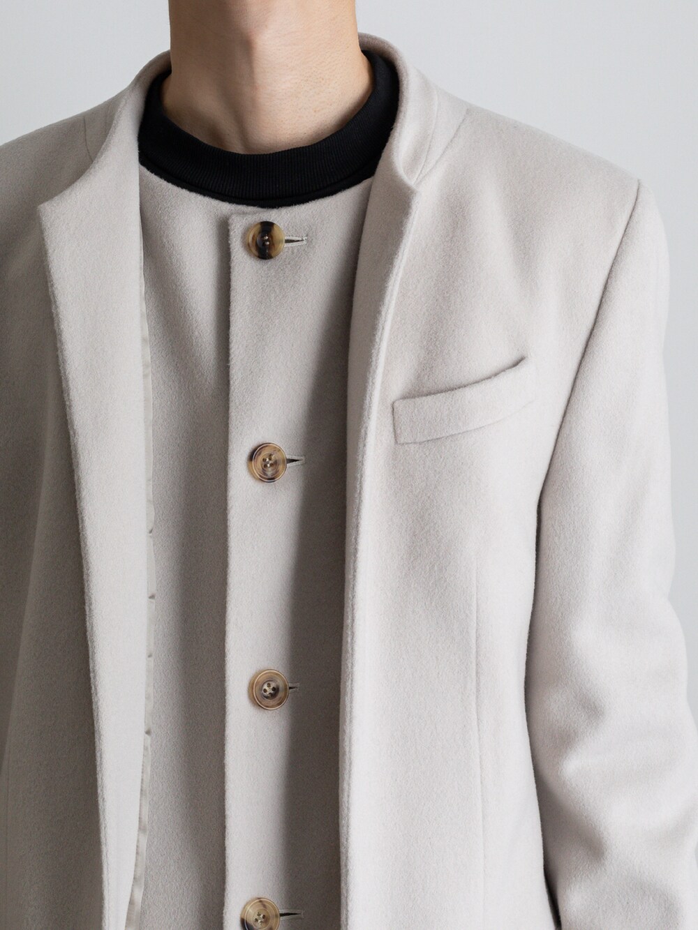 グレー系のその他パンツ、ホワイト系のノーカラーコートを着用したメンズの冬コーディネートの2枚目の写真