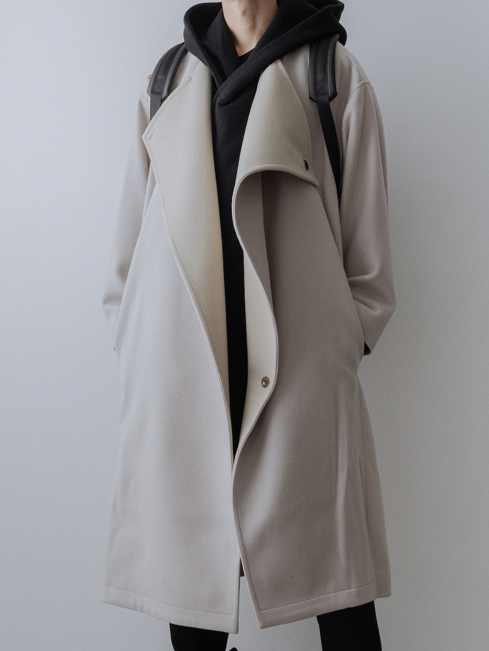 ホワイト系のチェスターコート、ブラック系のパーカー、ブラック系のその他パンツを着用したメンズの秋コーディネートの2枚目の写真