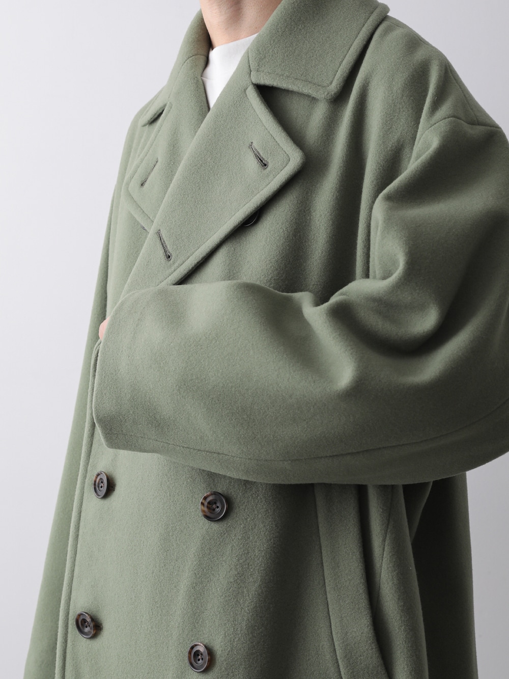 グリーン系のピーコート、グレー系のTシャツ/カットソー、ホワイト系のシャツ/ブラウスを着用したメンズの秋コーディネートの4枚目の写真