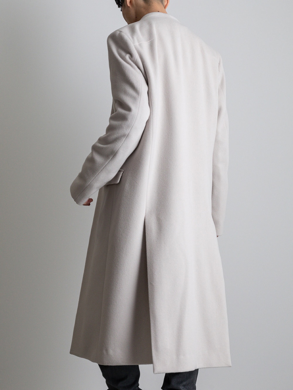 グレー系のその他パンツ、ホワイト系のノーカラーコートを着用したメンズの冬コーディネートの3枚目の写真