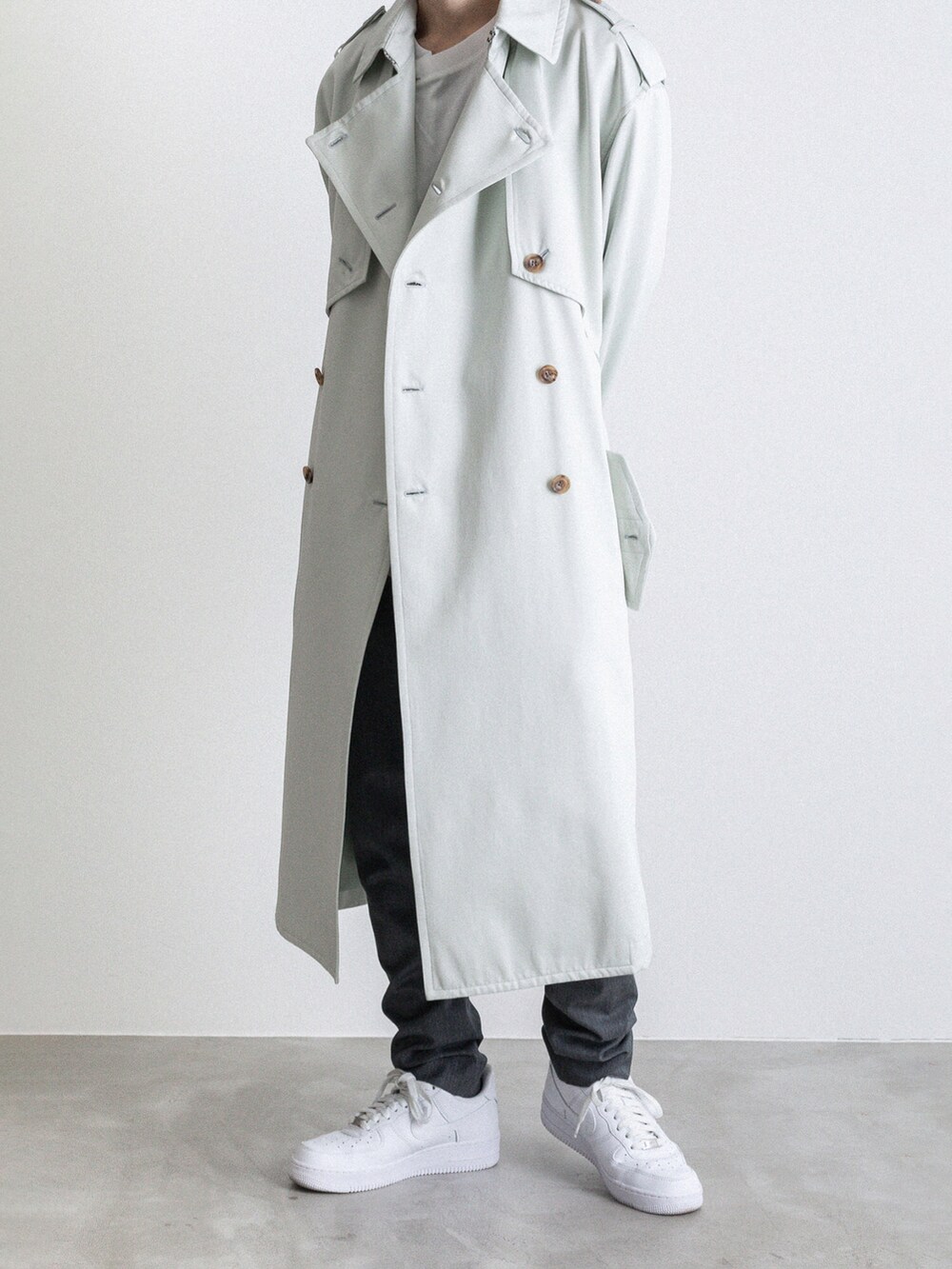 グリーン系のトレンチコート、ホワイト系のTシャツ/カットソー、グレー系のその他パンツを着用したメンズの冬コーディネートの2枚目の写真