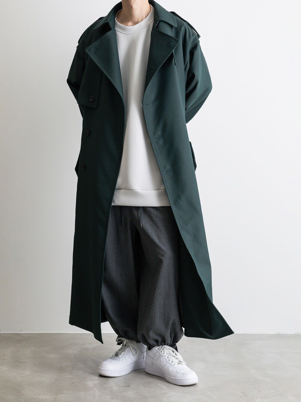 グレー系のその他パンツ、グレー系のTシャツ/カットソー、グリーン系のトレンチコートを着用したメンズの冬コーディネートの4枚目の写真