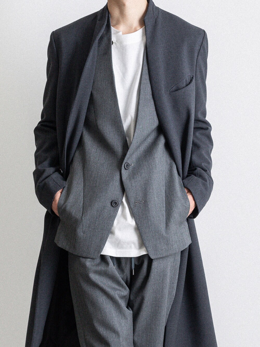 グレー系のノーカラージャケット、グレー系のその他パンツ、ホワイト系のTシャツ/カットソーを着用したメンズの冬コーディネートの2枚目の写真