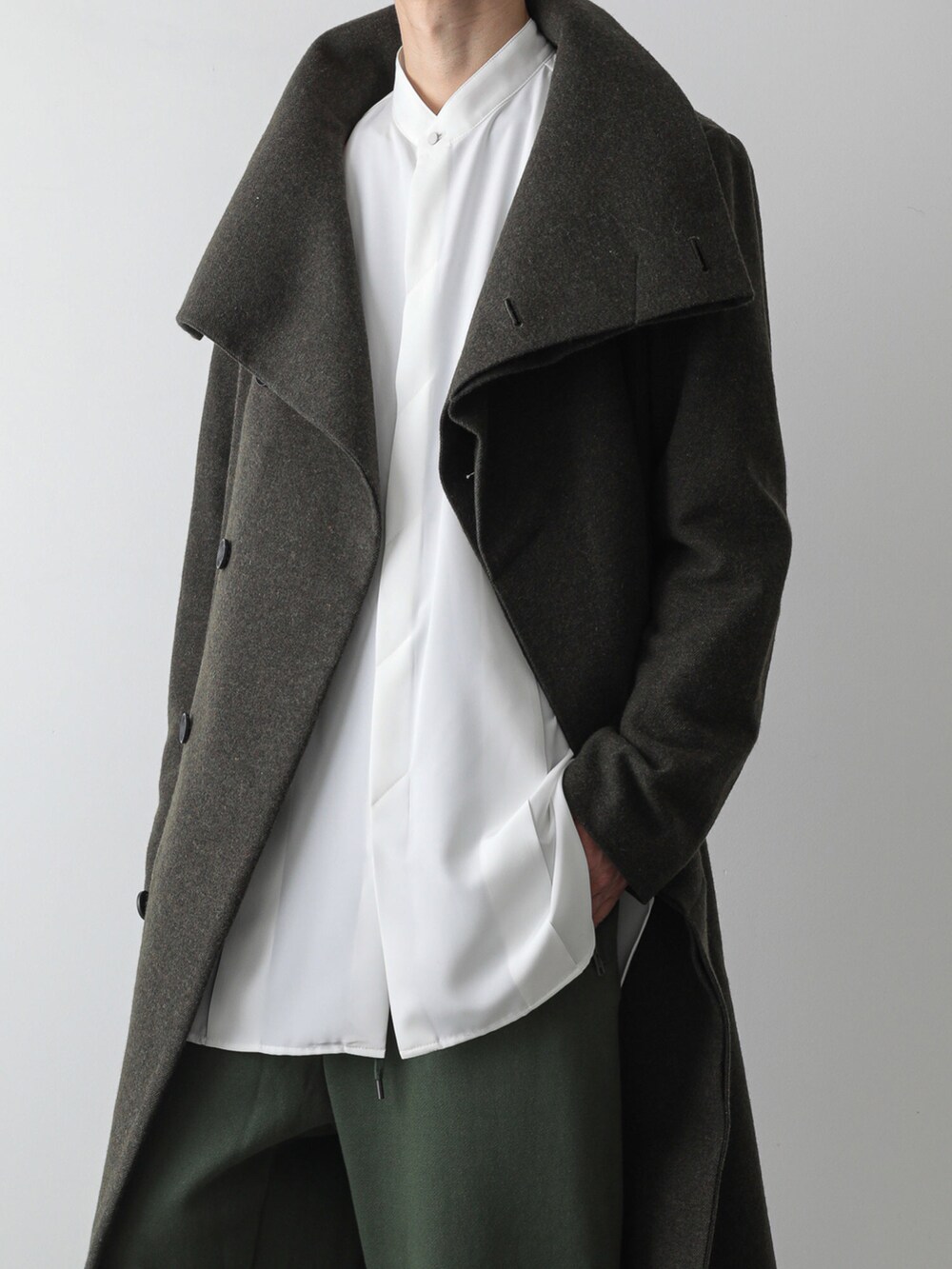 グリーン系のトレンチコート、ホワイト系のシャツ/ブラウス、グリーン系のスウェットパンツを着用したメンズの秋コーディネートの3枚目の写真