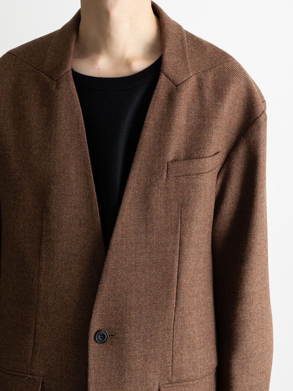 ブラウン系のノーカラージャケット、ブラック系のその他パンツ、ブラック系のTシャツ/カットソーを着用したメンズの冬コーディネートの2枚目の写真