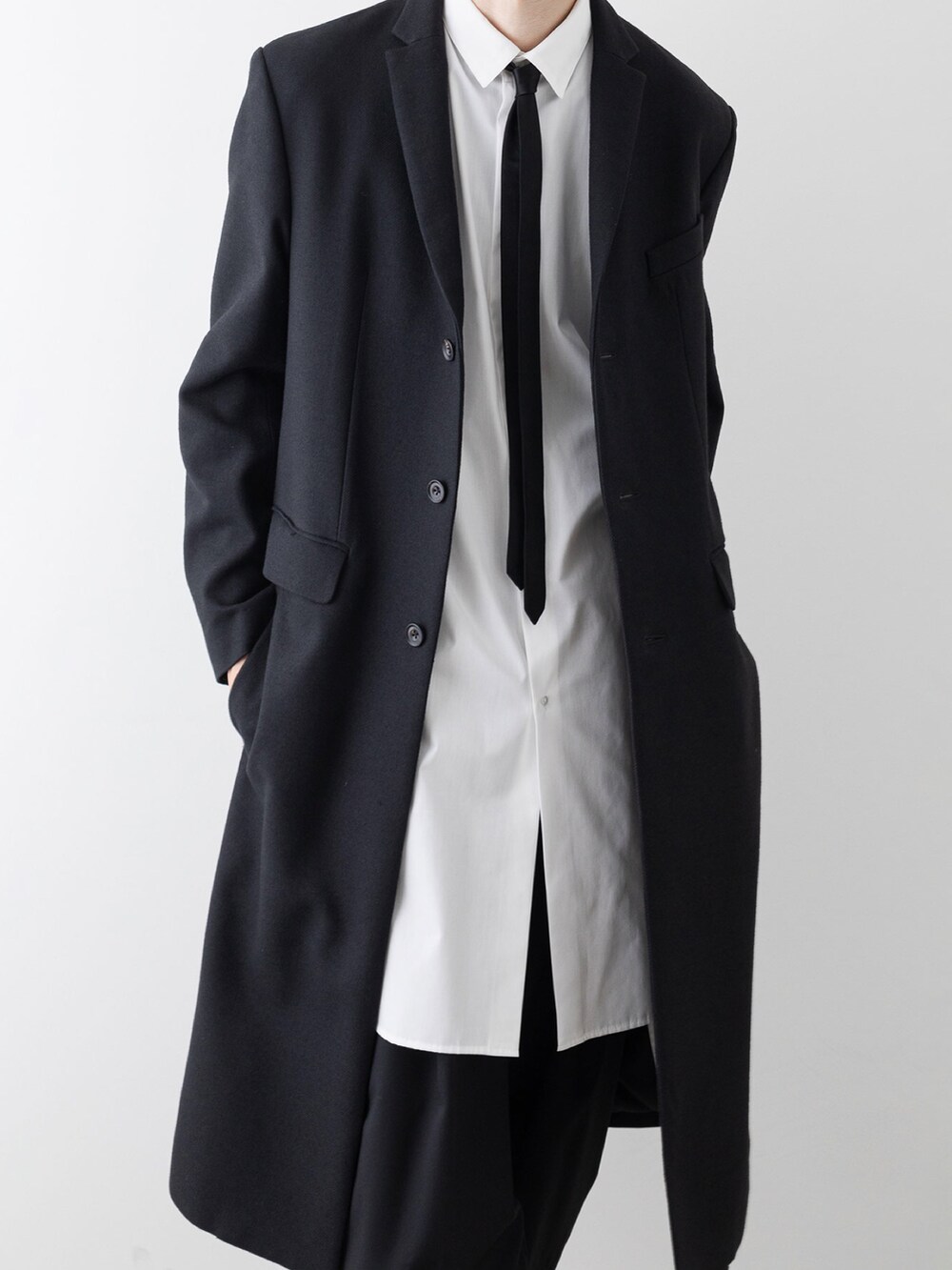 ブラック系のチェスターコート、ホワイト系のシャツ/ブラウス、ブラック系のその他パンツを着用したメンズの秋コーディネートの3枚目の写真