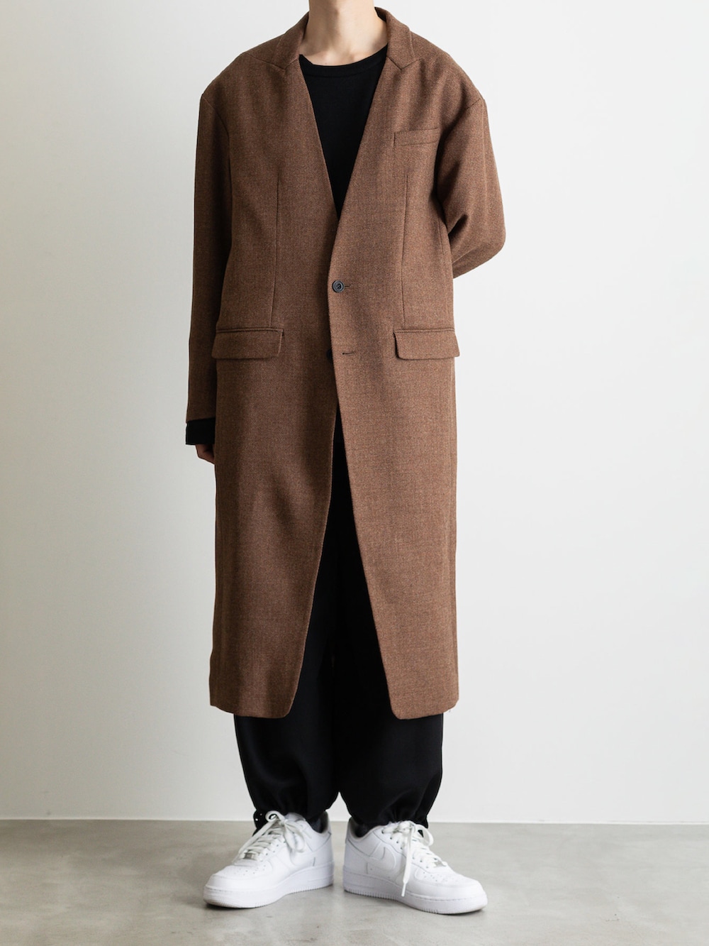 ブラック系のダウンベスト、ブラウン系のノーカラージャケット、ブラック系のその他パンツを着用したメンズの冬コーディネートの4枚目の写真