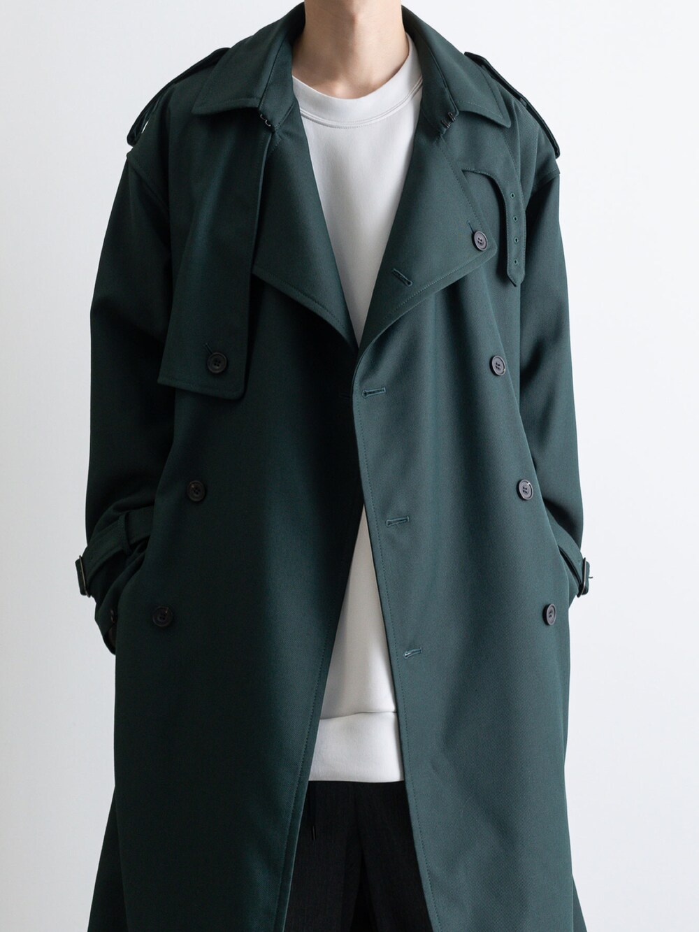 グレー系のその他パンツ、グレー系のTシャツ/カットソー、グリーン系のトレンチコートを着用したメンズの冬コーディネートの2枚目の写真