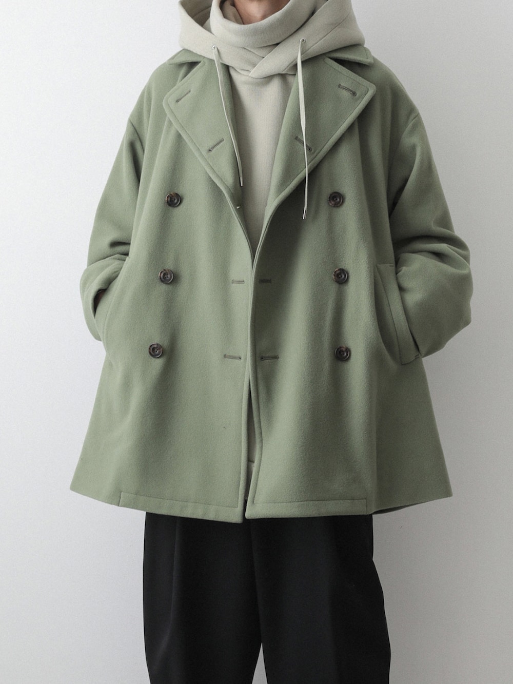 グリーン系のピーコート、グリーン系のパーカー、ブラック系のその他パンツを着用したメンズの秋コーディネートの2枚目の写真