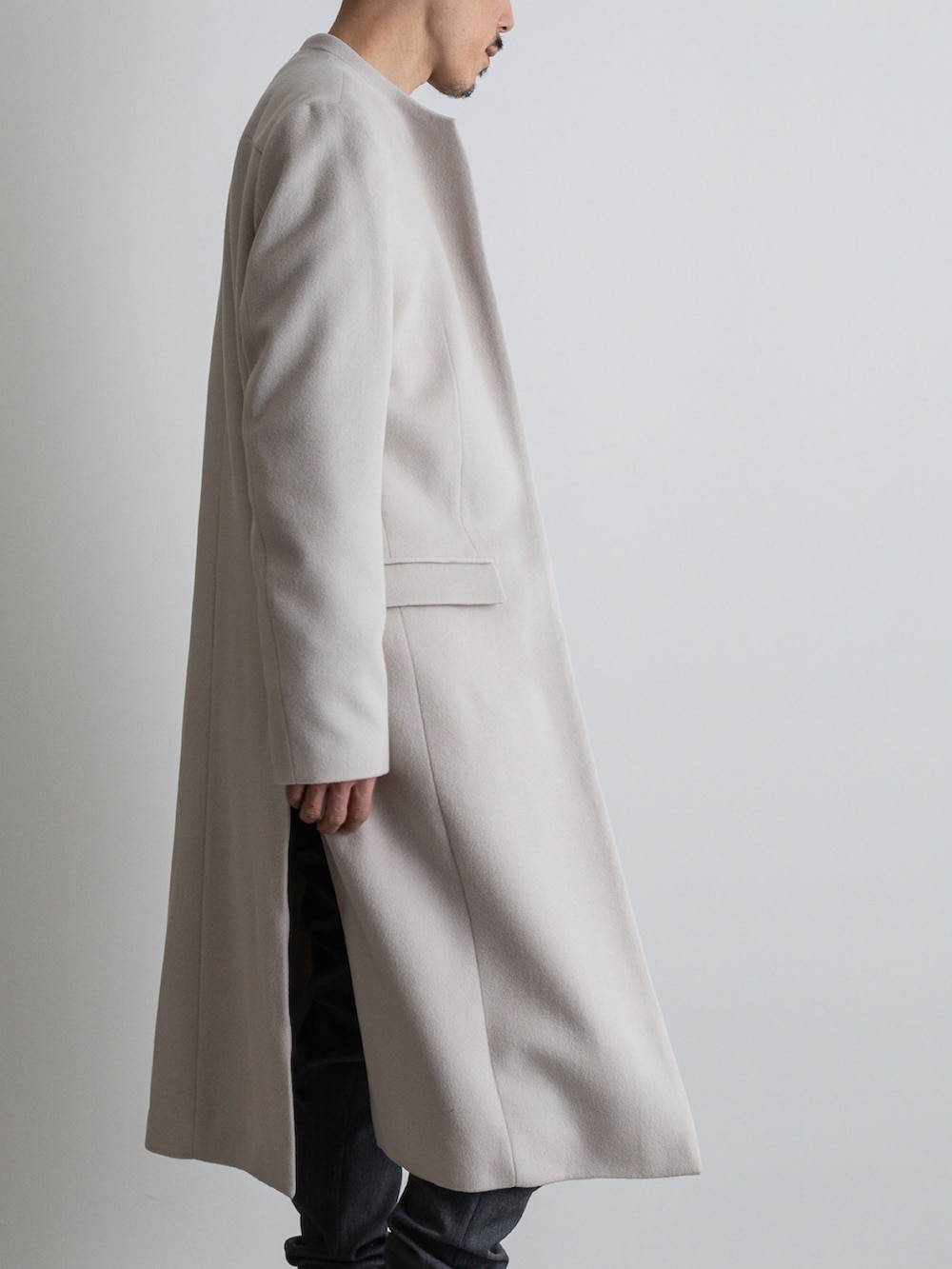 グレー系のその他パンツ、ホワイト系のノーカラーコートを着用したメンズの冬コーディネートの5枚目の写真