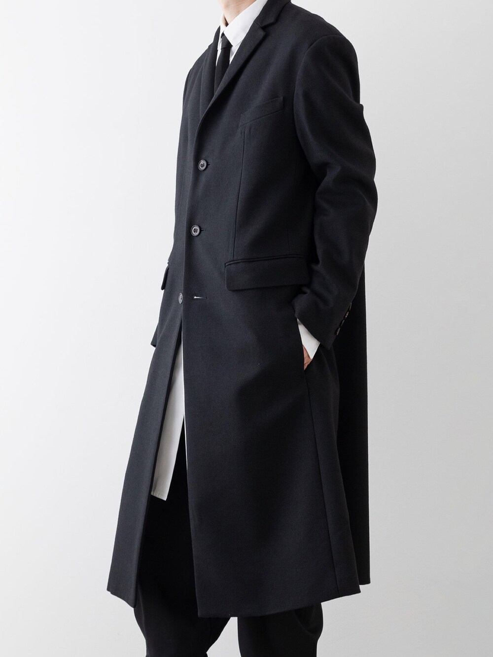 ブラック系のチェスターコート、ホワイト系のシャツ/ブラウス、ブラック系のその他パンツを着用したメンズの秋コーディネートの2枚目の写真