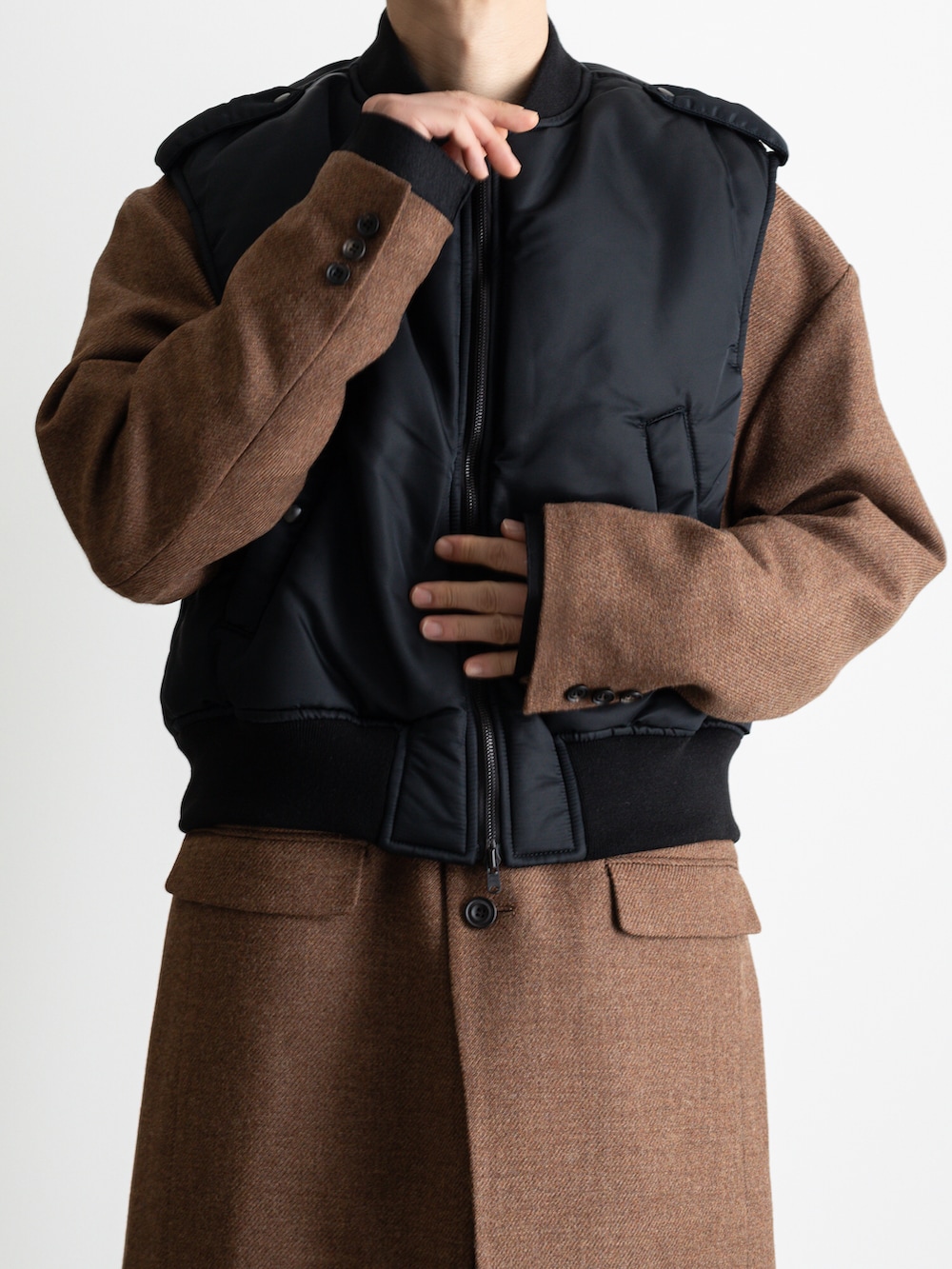 ブラック系のダウンベスト、ブラウン系のノーカラージャケット、ブラック系のその他パンツを着用したメンズの冬コーディネートの3枚目の写真