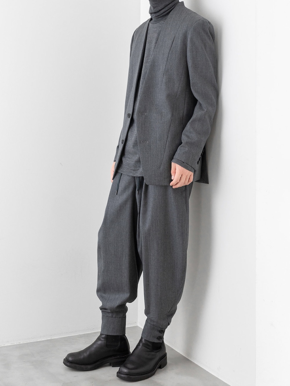 グレー系のノーカラージャケット、グレー系のニット/セーター、ブラック系のチェスターコートを着用したメンズの秋コーディネートの3枚目の写真