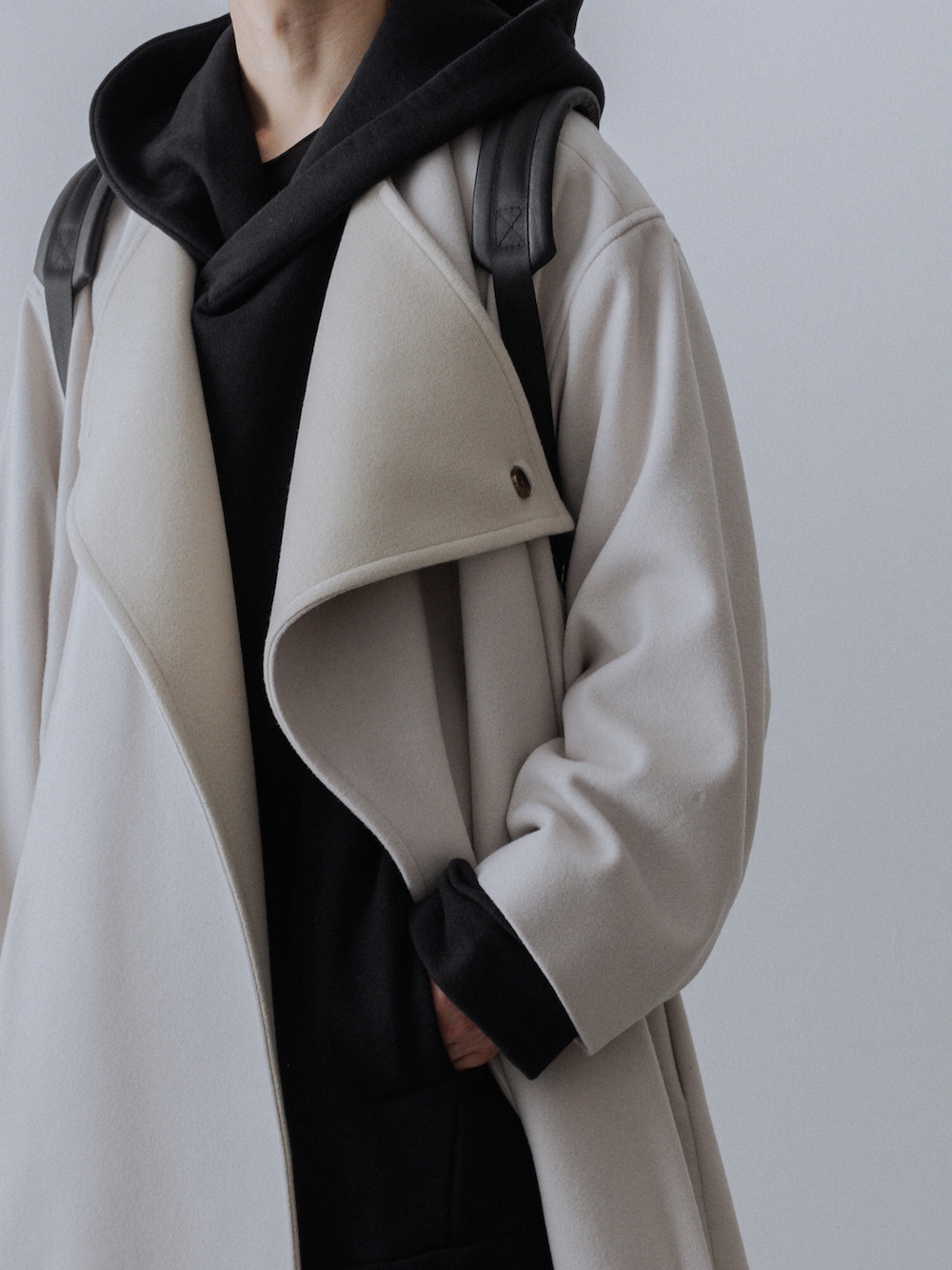 ホワイト系のチェスターコート、ブラック系のパーカー、ブラック系のその他パンツを着用したメンズの秋コーディネートの3枚目の写真