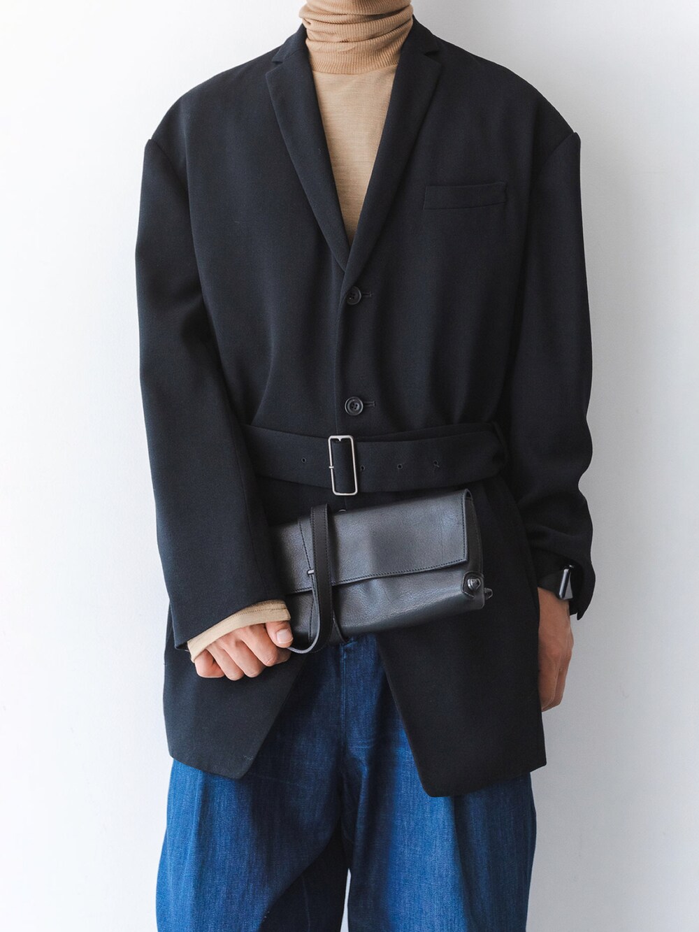 ブラック系のバッグ、ブラック系のテーラードジャケット、ブルー系のデニムパンツを着用したメンズの秋コーディネートの2枚目の写真