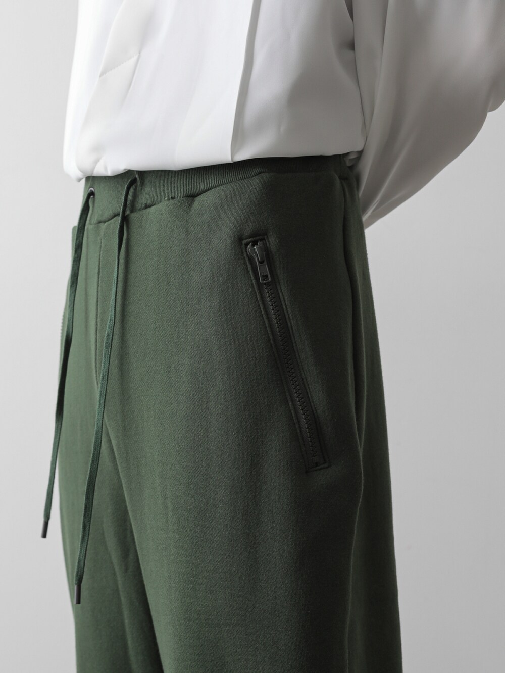 グリーン系のトレンチコート、ホワイト系のシャツ/ブラウス、グリーン系のスウェットパンツを着用したメンズの秋コーディネートの5枚目の写真