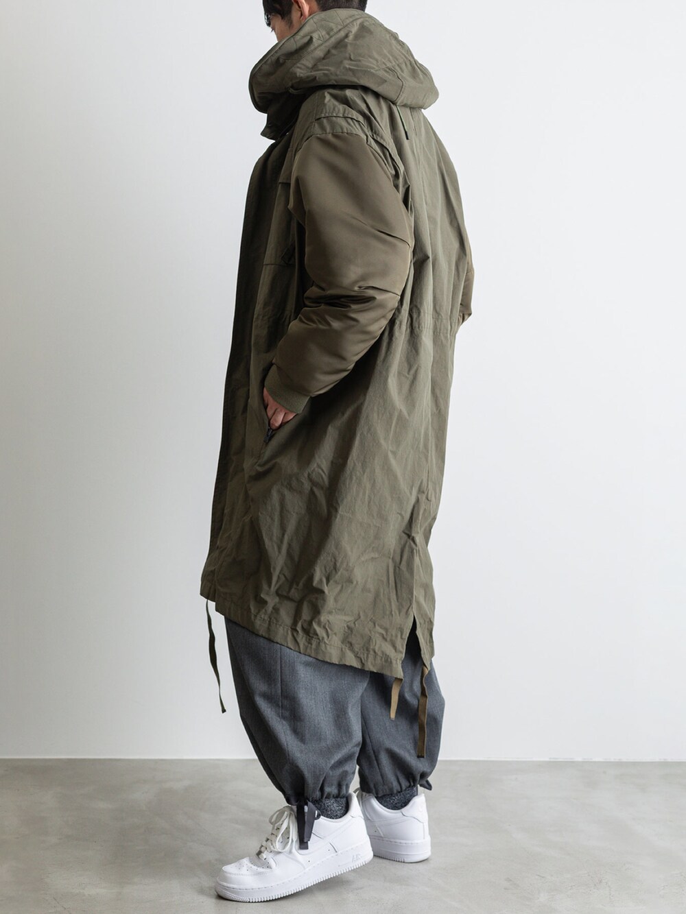 グリーン系のモッズコート、グレー系のその他パンツ、グレー系のTシャツ/カットソーを着用したメンズの冬コーディネートの2枚目の写真