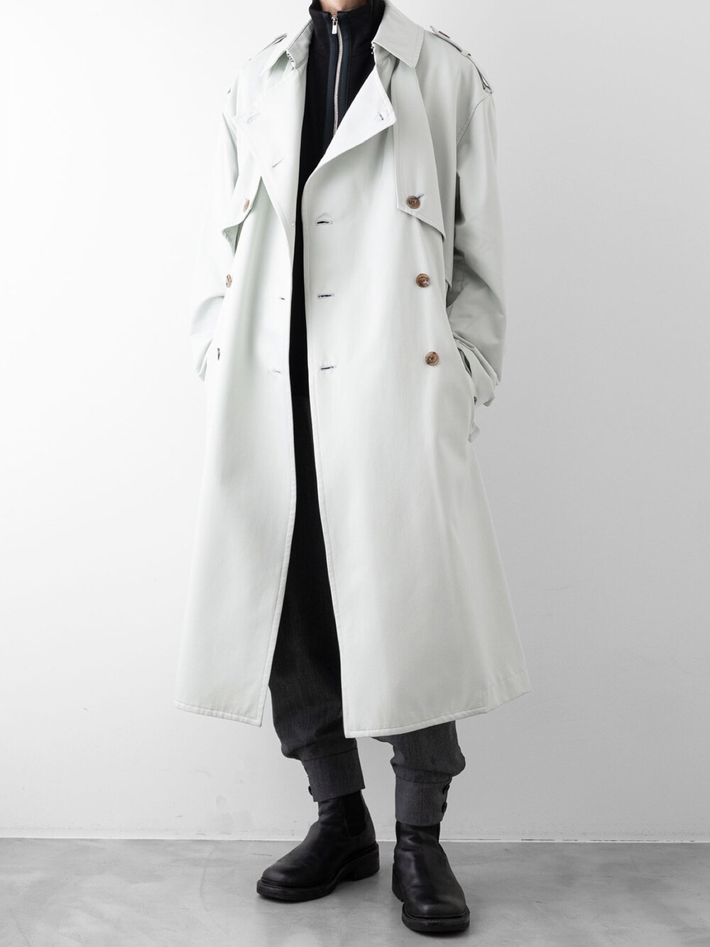 グレー系のその他パンツ、ブラック系のニット/セーター、グリーン系のトレンチコートを着用したメンズの秋コーディネートの4枚目の写真