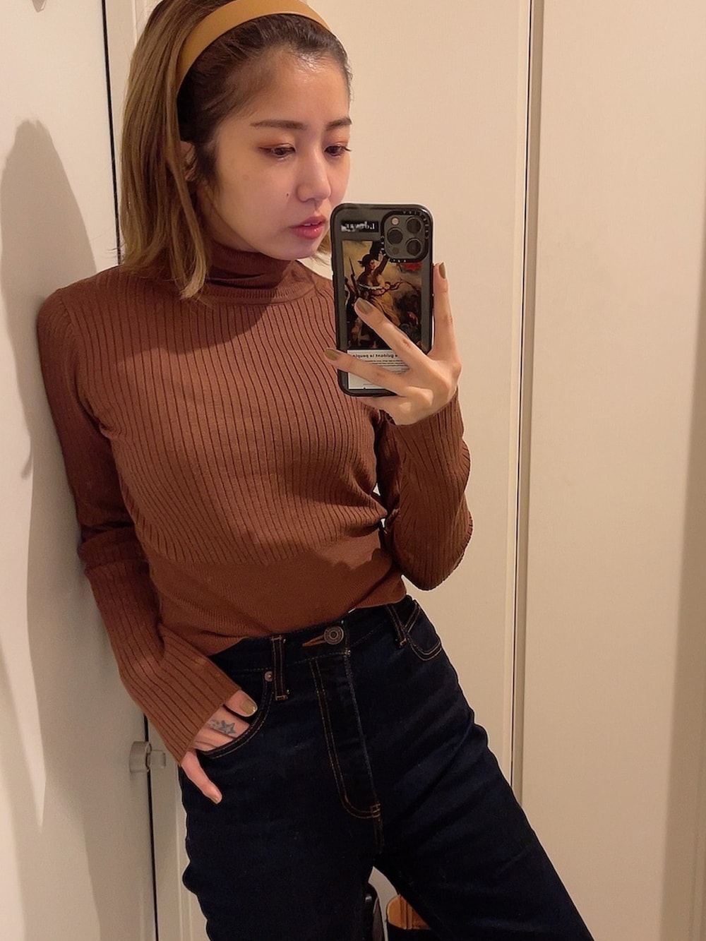 ブラウン系のニット/セーター、ブルー系のデニムパンツを着用したレディースの冬コーディネートの2枚目の写真