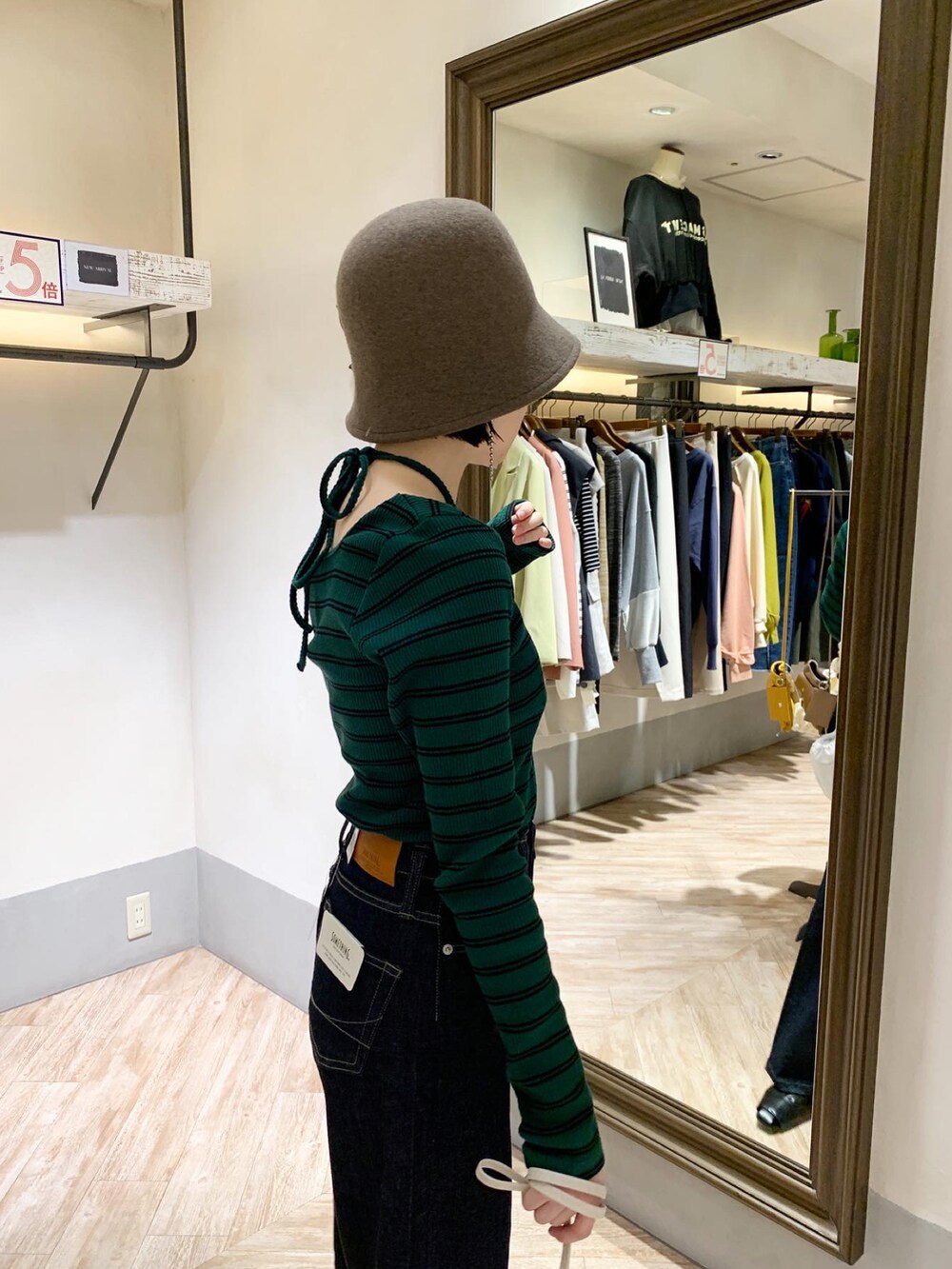 グリーン系のTシャツ/カットソー、ブルー系のデニムパンツ、ブラウン系のハットを着用したレディースの秋コーディネートの2枚目の写真