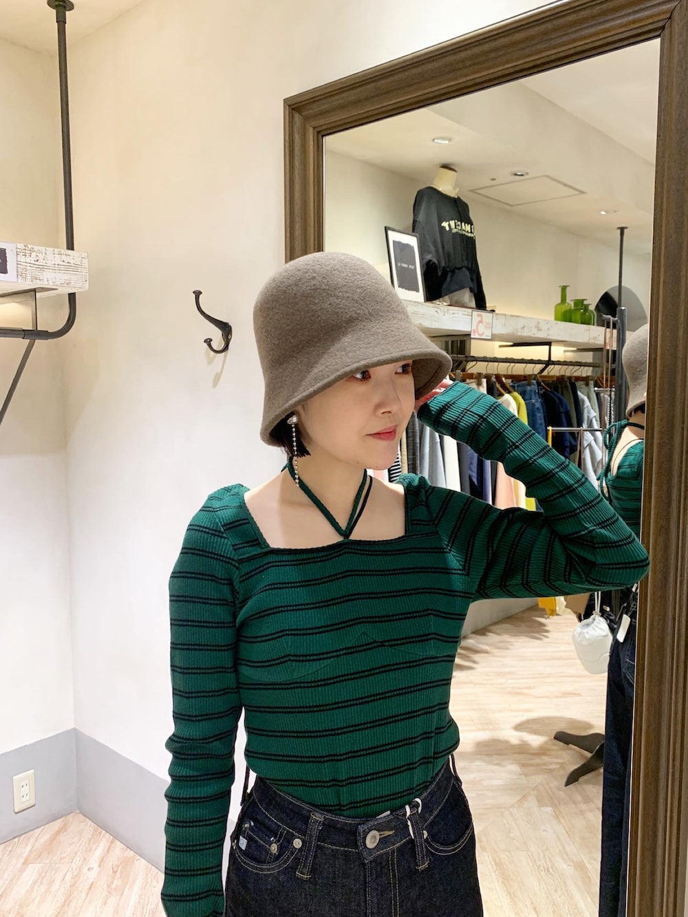 グリーン系のTシャツ/カットソー、ブルー系のデニムパンツ、ブラウン系のハットを着用したレディースの秋コーディネートの3枚目の写真