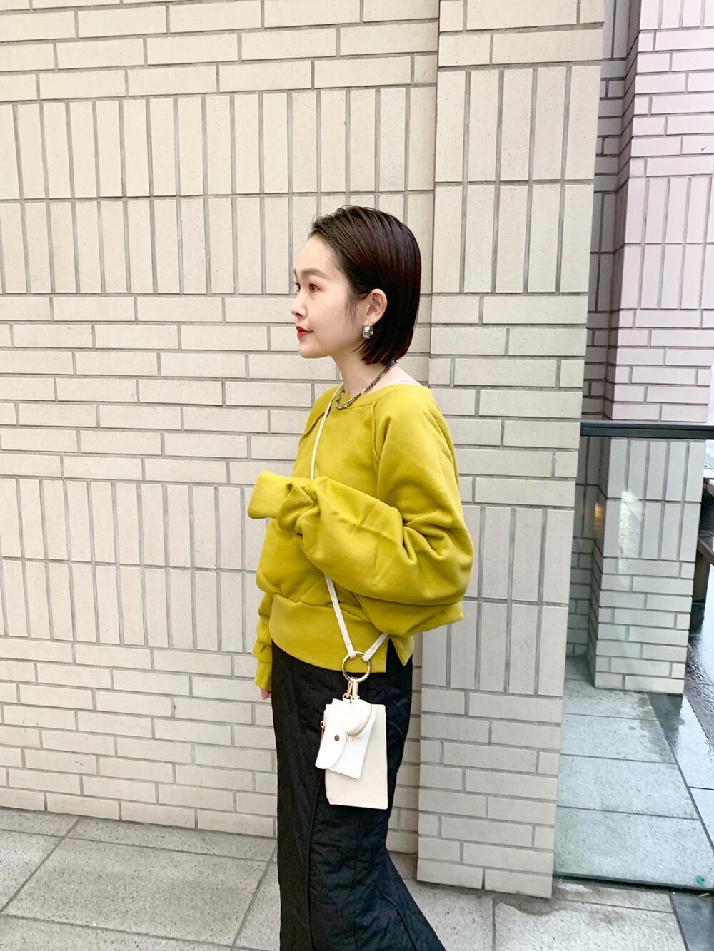 イエロー系のスウェット、ブラック系のスカートを着用したレディースの秋コーディネートの2枚目の写真