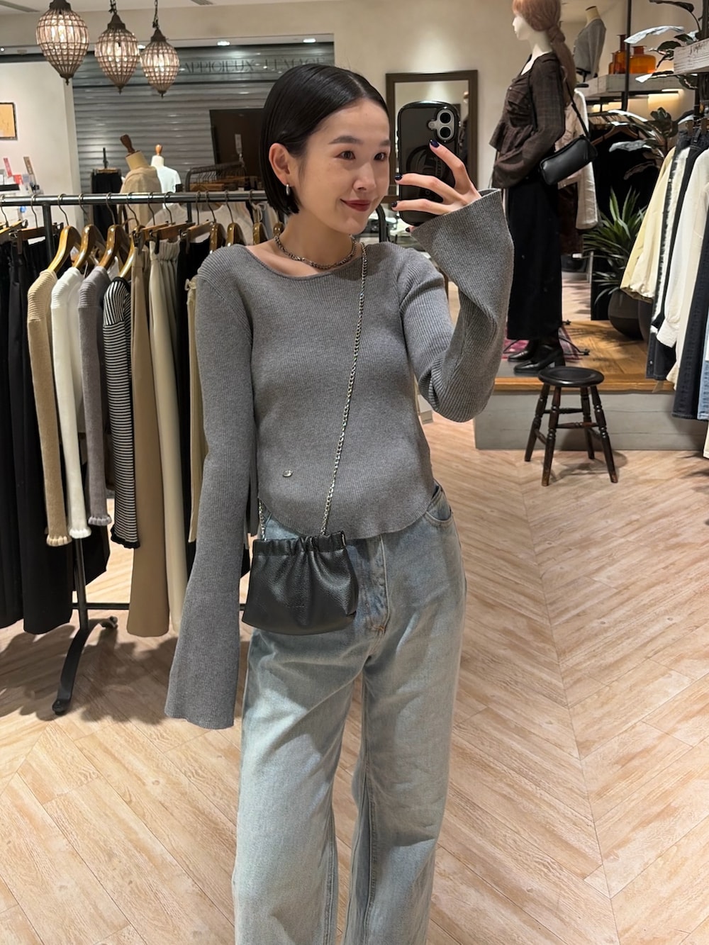 グレー系のニット/セーター、ブルー系のデニムパンツ、ブラック系のショルダーバッグを着用したレディースの秋コーディネートの2枚目の写真
