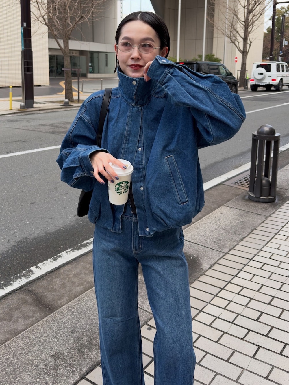 ブルー系のブルゾン、ブルー系のデニムパンツ、ブラック系のショルダーバッグを着用したレディースの冬コーディネートの2枚目の写真