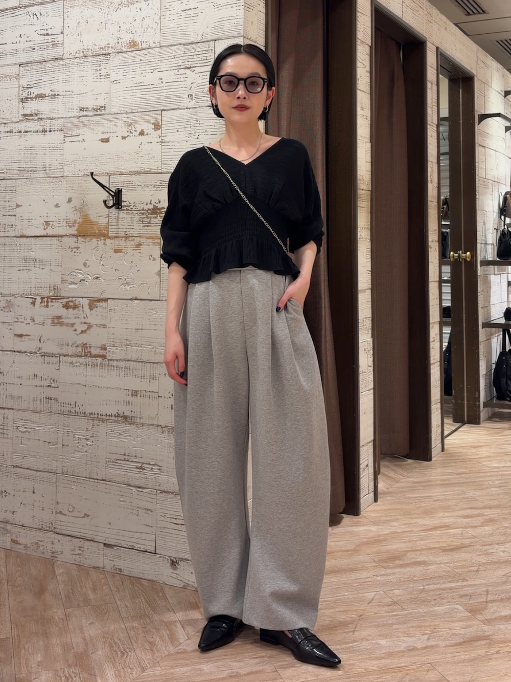 ブラック系のシャツ/ブラウス、グレー系のその他パンツ、ホワイト系のショルダーバッグを着用したレディースの春コーディネートの2枚目の写真