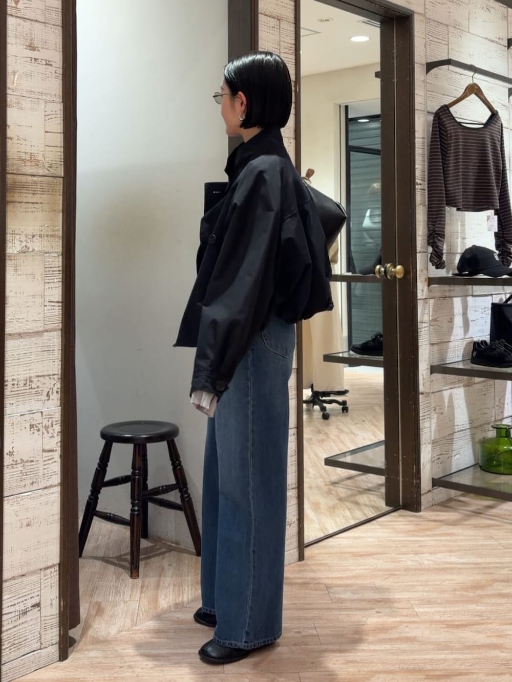 ブラック系のトレンチコート、ブルー系のデニムパンツ、ブラック系のベルトを着用したレディースの春コーディネートの2枚目の写真