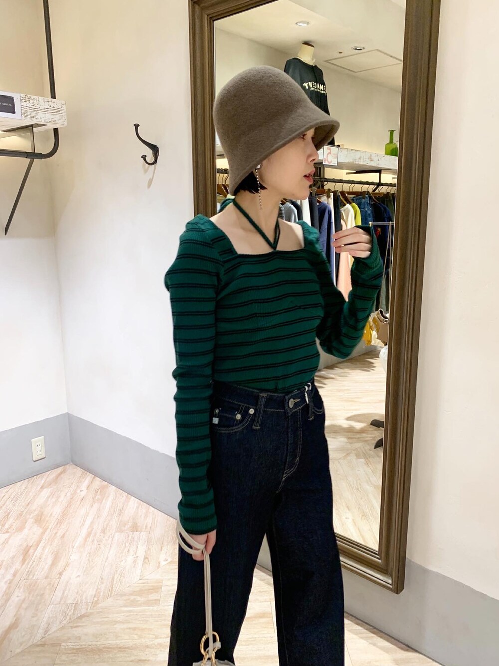 グリーン系のTシャツ/カットソー、ブルー系のデニムパンツ、ブラウン系のハットを着用したレディースの秋コーディネートの4枚目の写真