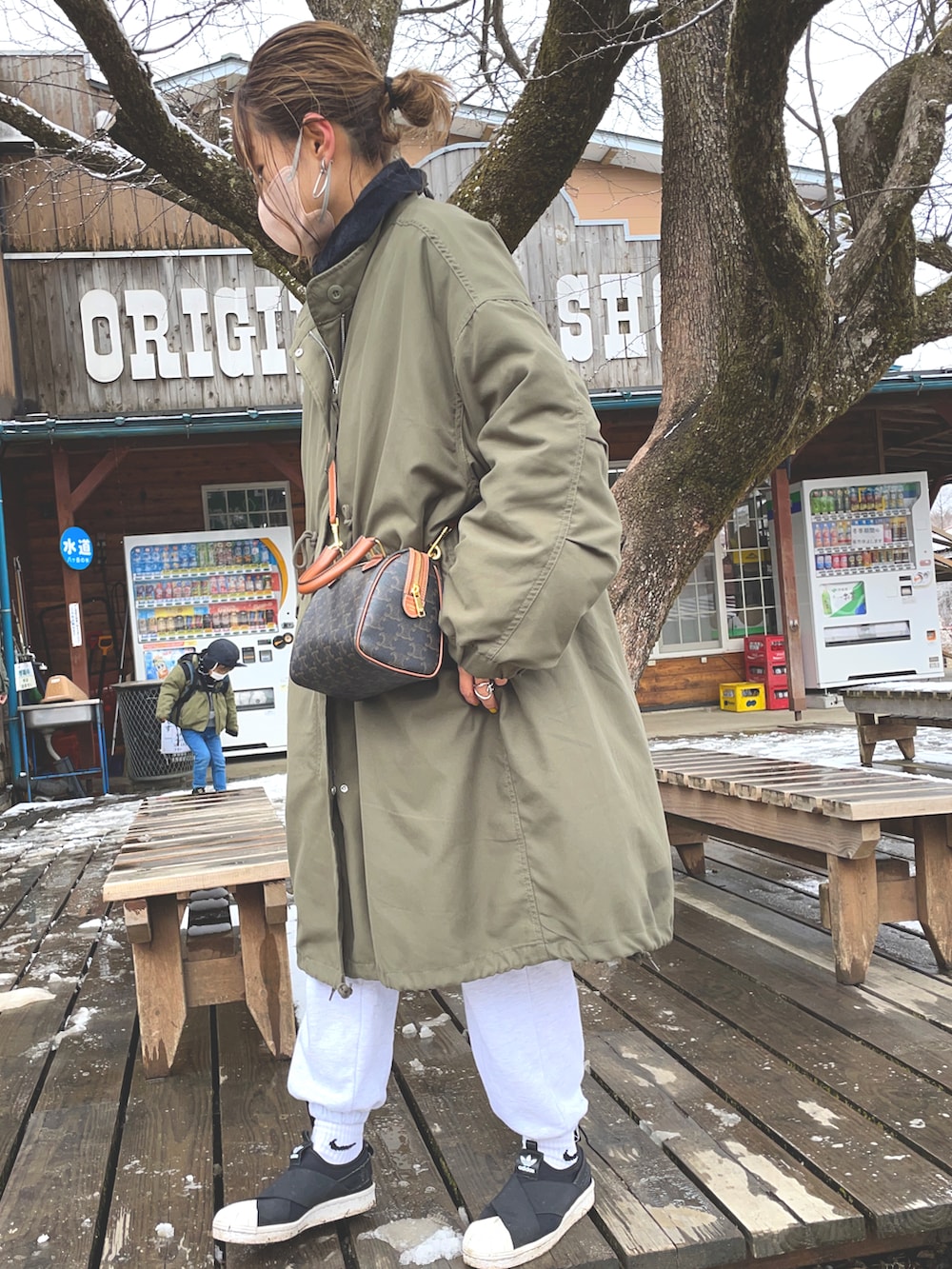 ブラック系のスニーカー、グリーン系のモッズコート、ホワイト系のスウェットパンツを着用したレディースの春コーディネートの4枚目の写真